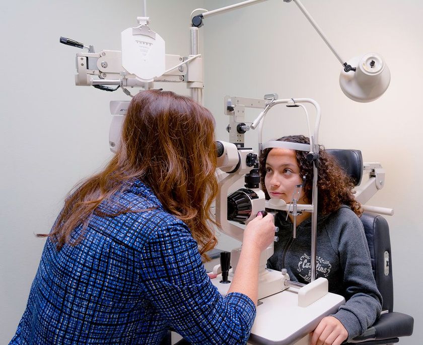 Optometrist performing a vision test on a young teenage girl