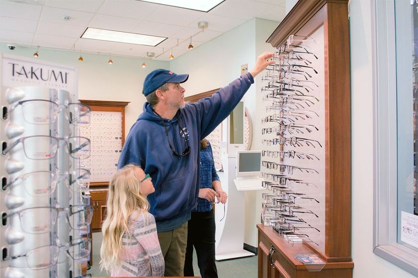 A man and his daughter are shopping for eyeglasses