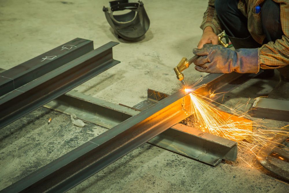 A Man Is Cutting A Piece Of Metal With A Torch — Tinman's Welding Worx In Sarina, QLD