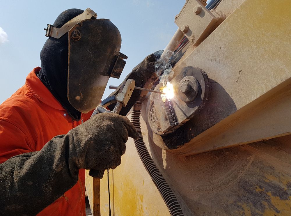 A Man Wearing A Welding Mask Is Welding A Piece Of Metal — Tinman's Welding Worx In Mackay, QLD