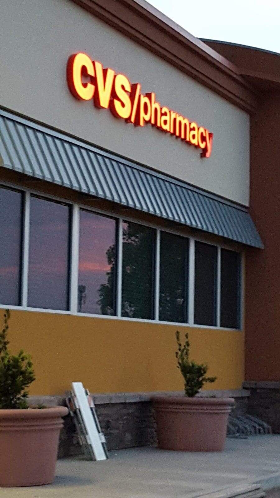 A CVS/pharmacy storefront sign in yellow and red, with large windows, planters, and a slanted metal awning.