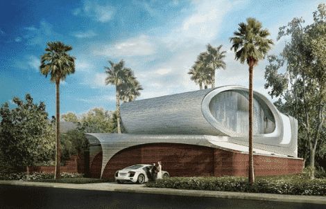 A futuristic, oval-shaped house with a silver exterior and brick base sits among palm trees, with a white car parked outside.