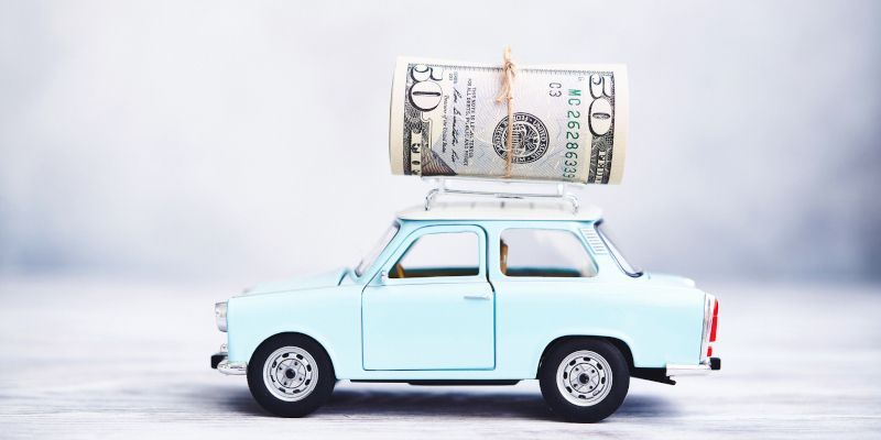 A toy car with a stack of money on top of it.