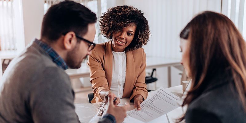A man and a woman are sitting at a table talking to a woman.