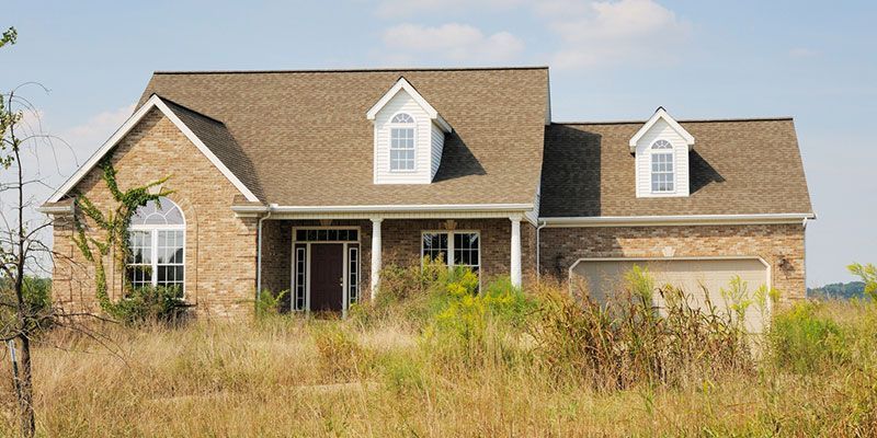 A brick house sits in the middle of a grassy field