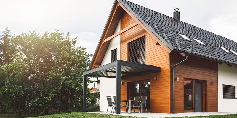 A large house with a wooden roof and a pergola in the backyard.