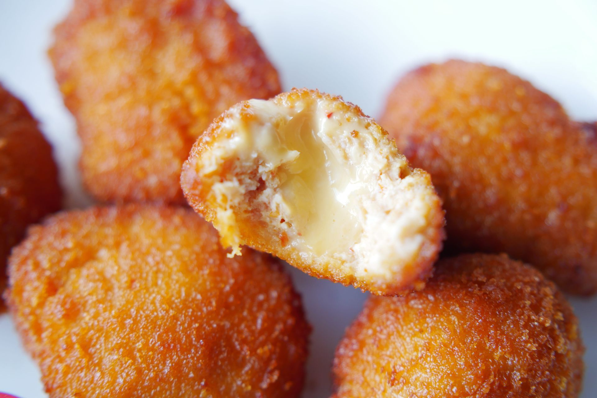 Golden fried dough balls with one bitten open to reveal a creamy filling