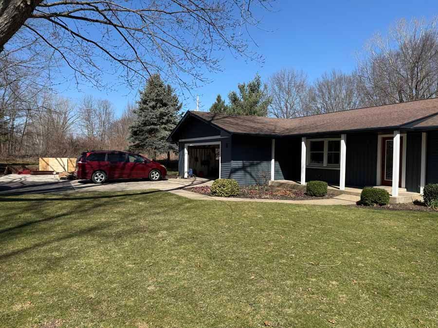 Suburban ranch house with a red van parked in the driveway and a large front lawn