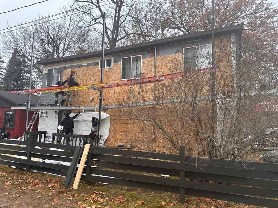 Firefighters using an extended ladder to reach a second-story townhouse window after a fire
