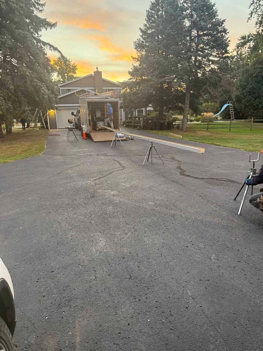 Driveway leading to a small pavilion at sunset, with trees and equipment on both sides.