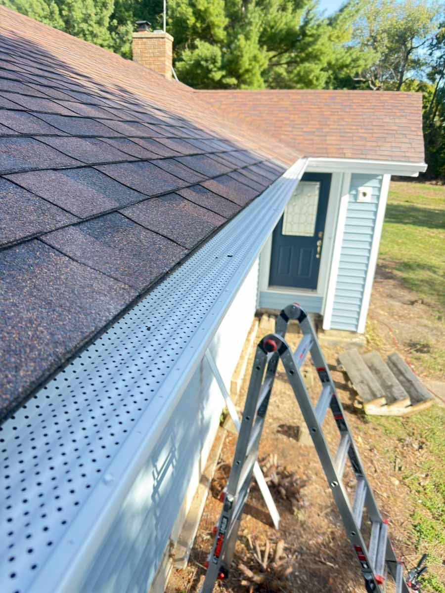 Ladder at a house roof edge with gutter and soffit repair work in progress