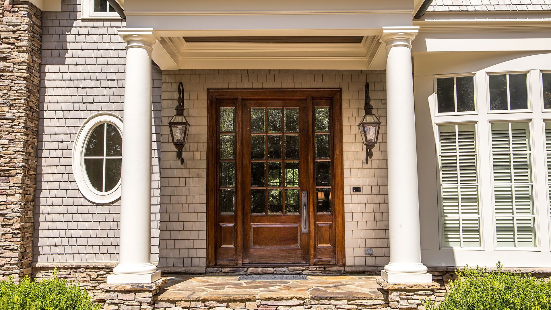 Front entrance of a brick house with wooden double doors and white columns