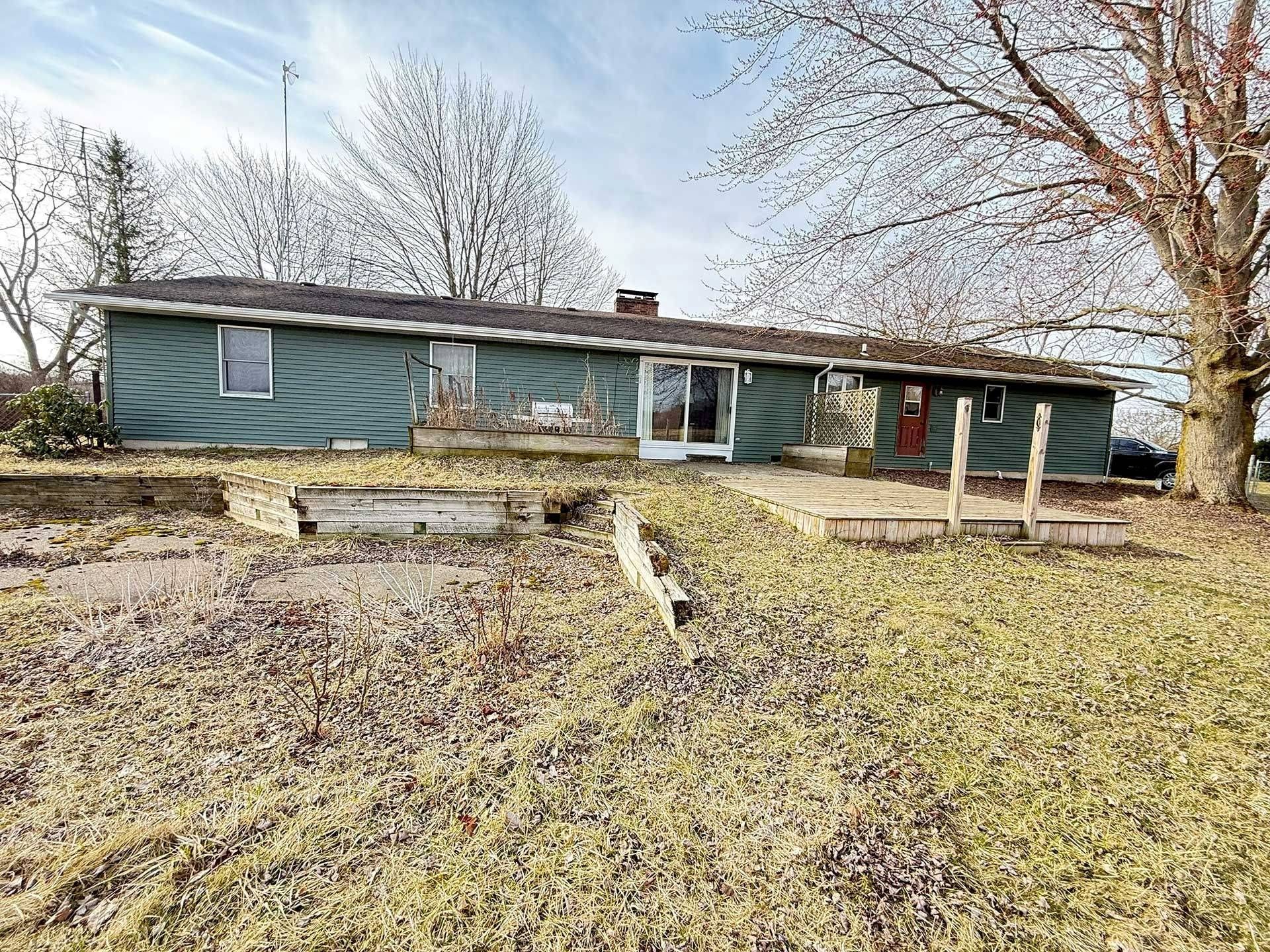 Single-story house with a sagging roof, bare trees, and a muddy yard in winter.