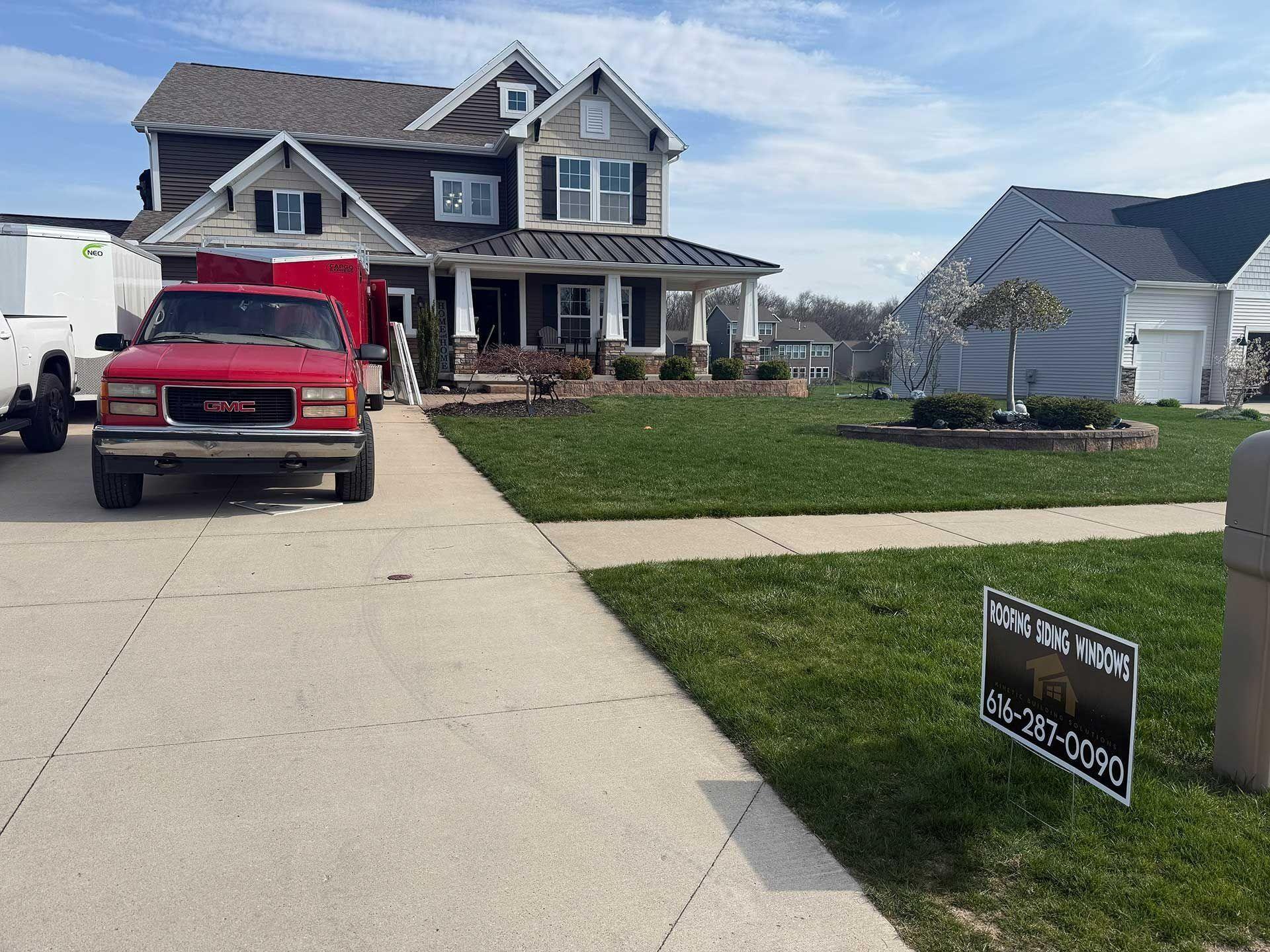Suburban house with a red truck in the driveway and a real estate sign on the lawn.