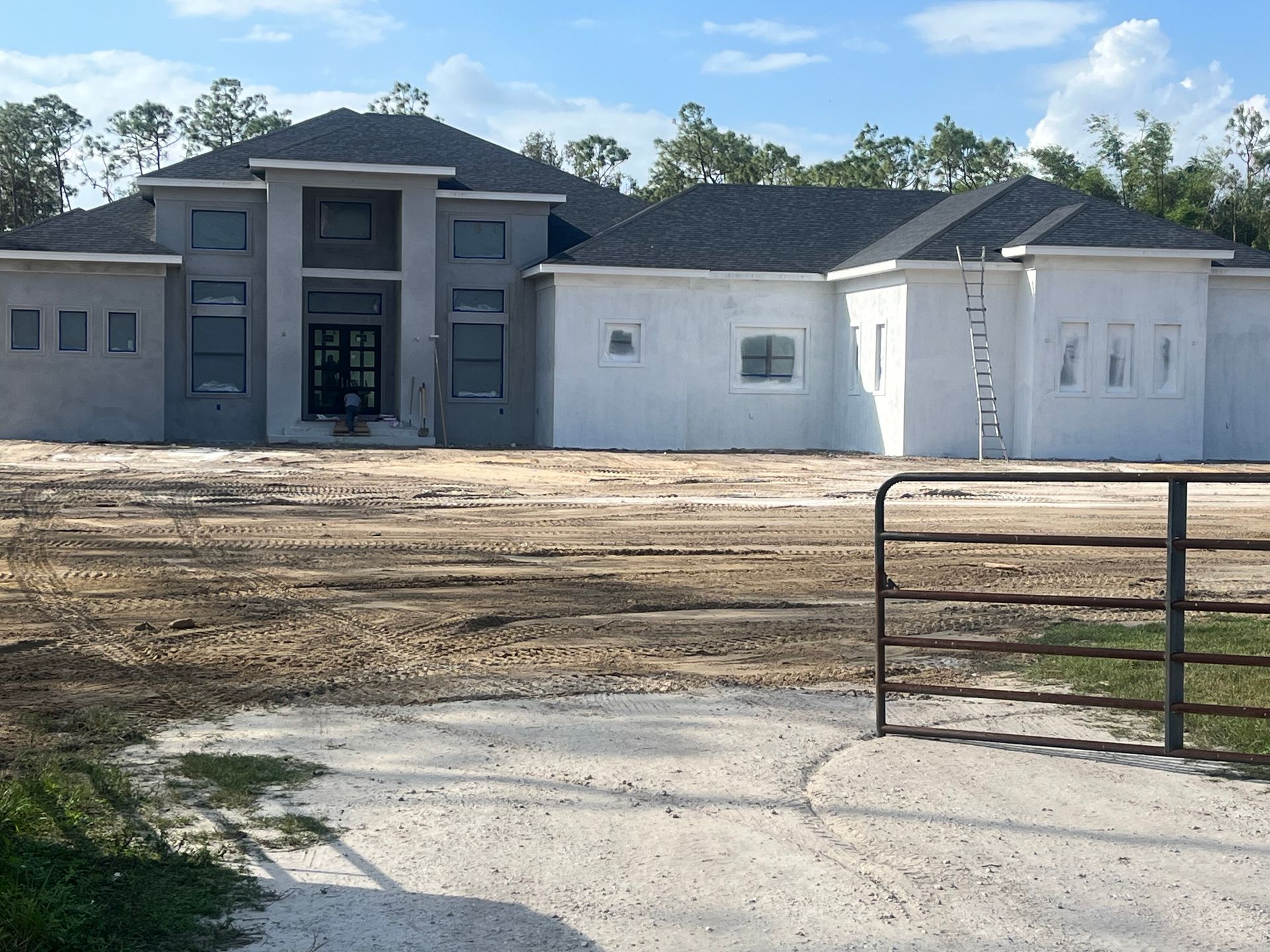 New house under construction with gray and white exterior and a dirt front yard