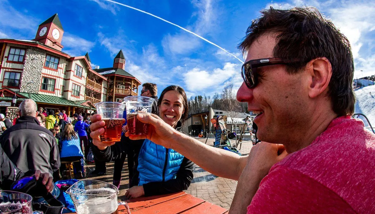 People toasting drinks outdoors at a lively street festival on a sunny day.