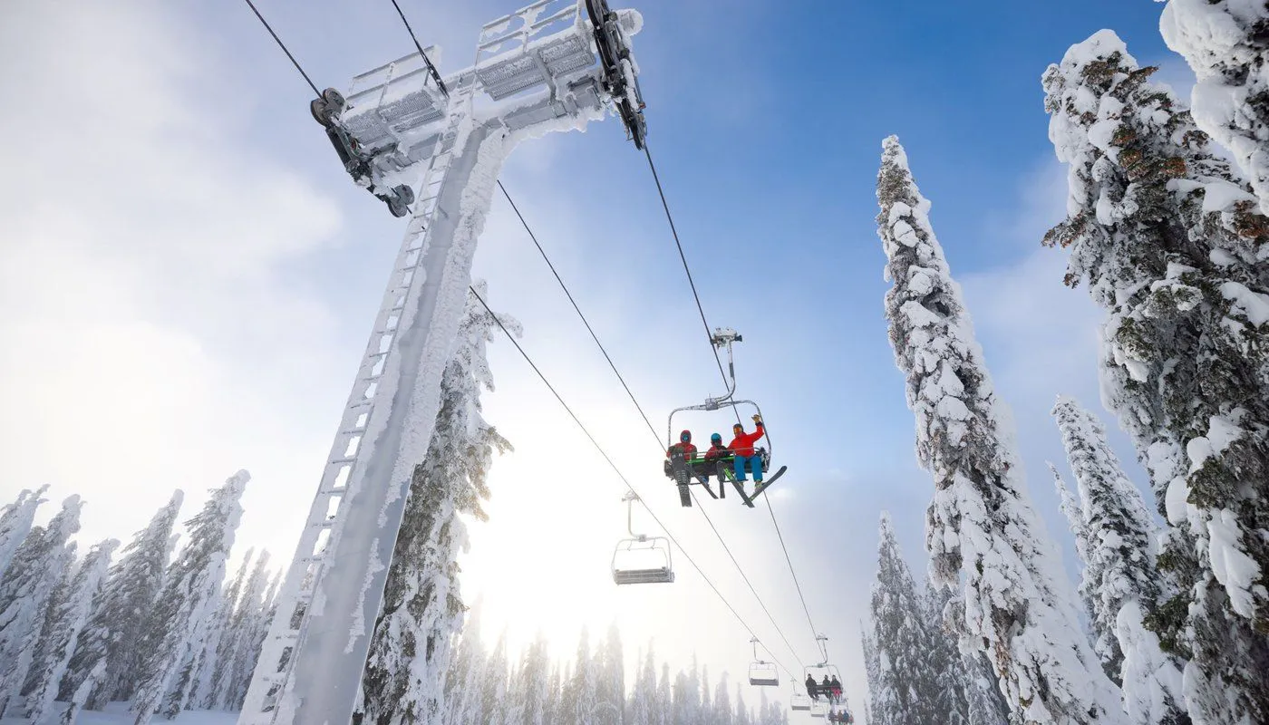 Ski lift gliding over snow-covered trees on a bright winter mountain