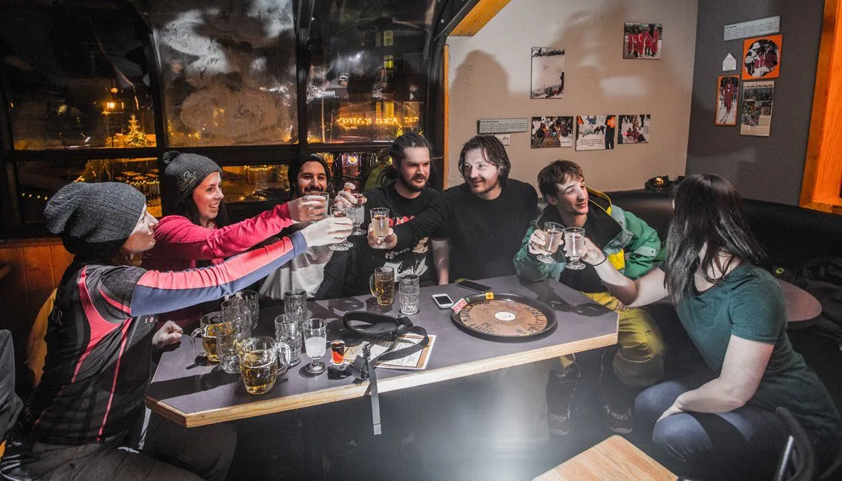 Friends raising glasses around a cluttered table in a cozy, dimly lit restaurant