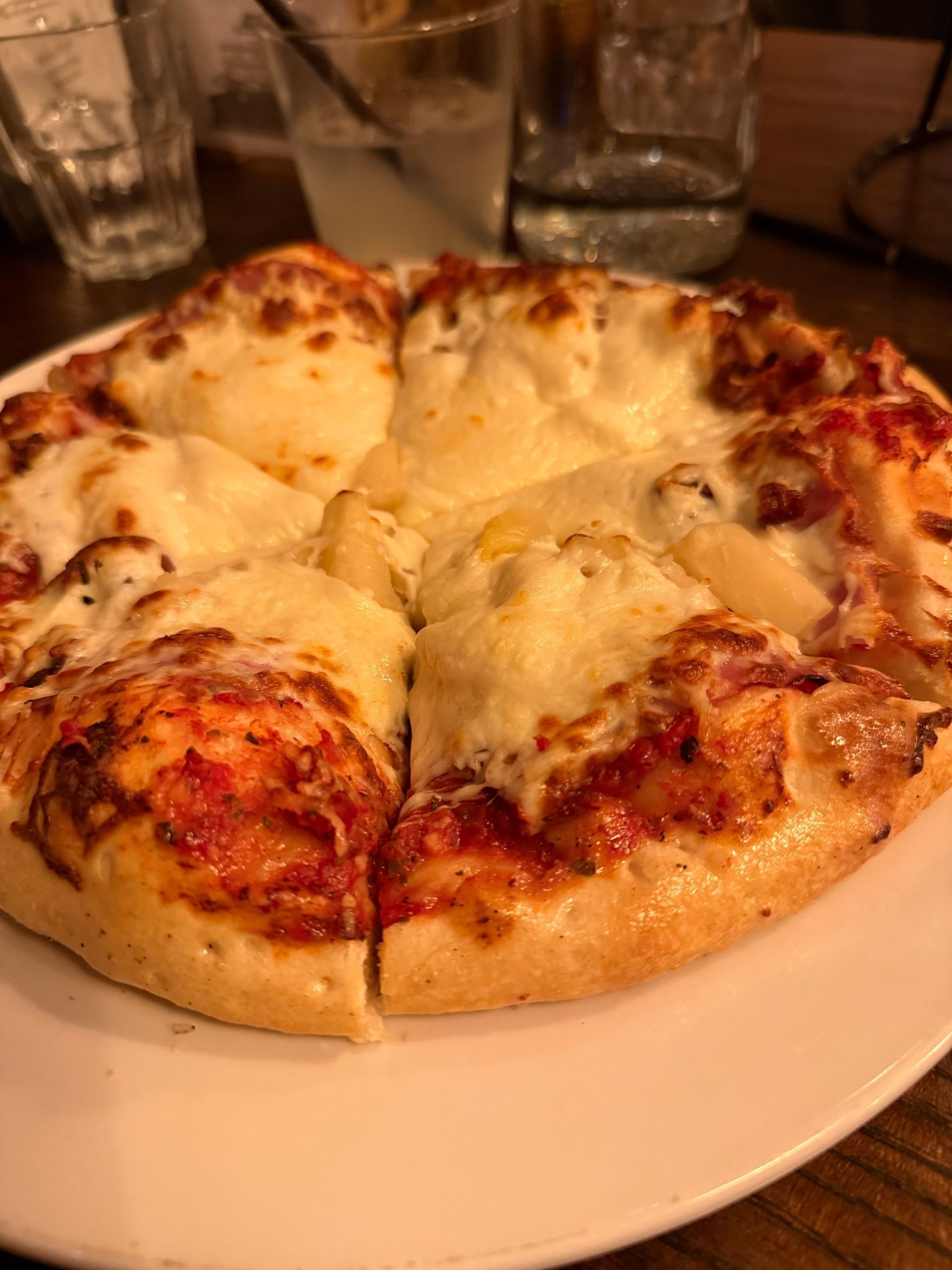 Cheese pizza on a white plate in a warm-lit restaurant setting