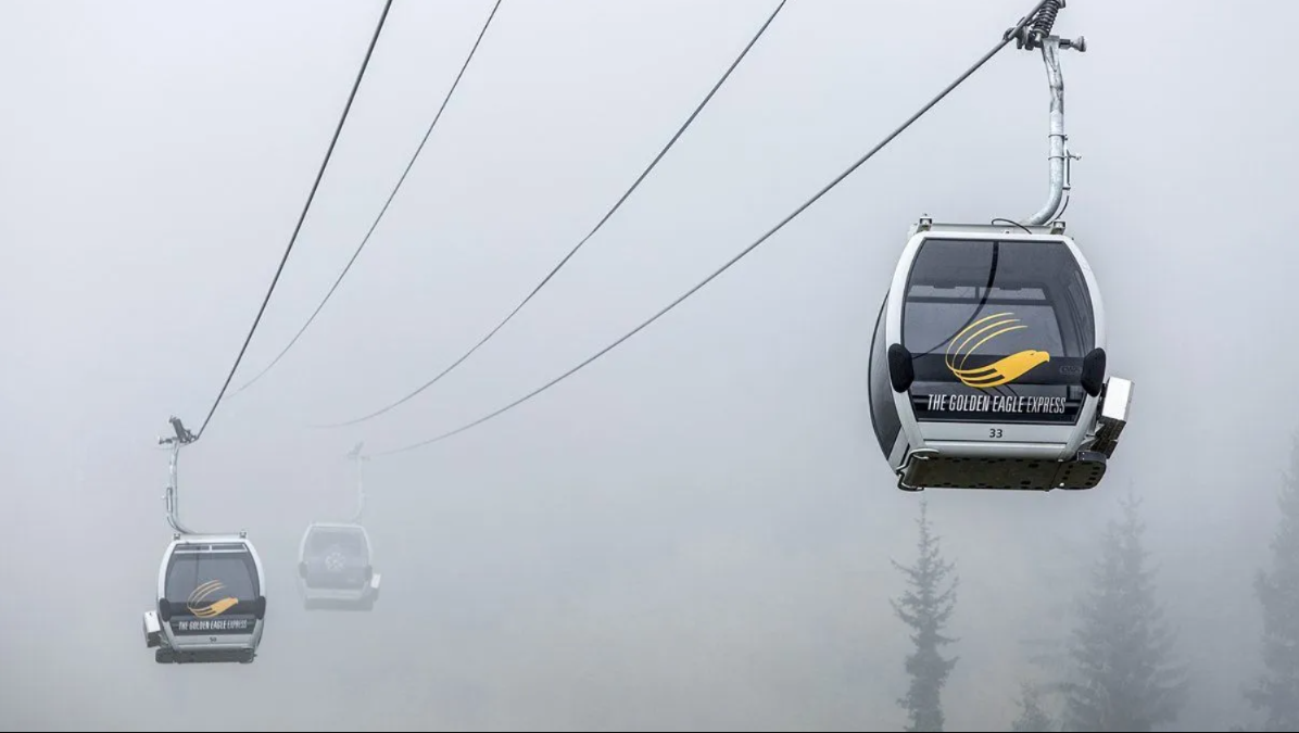 Foggy mountain cable cars suspended on wires, with one gondola close in the foreground