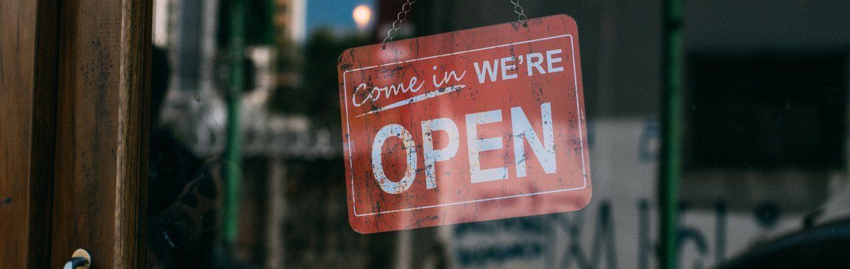 Red “WE’RE OPEN” sign hanging in a shop window.
