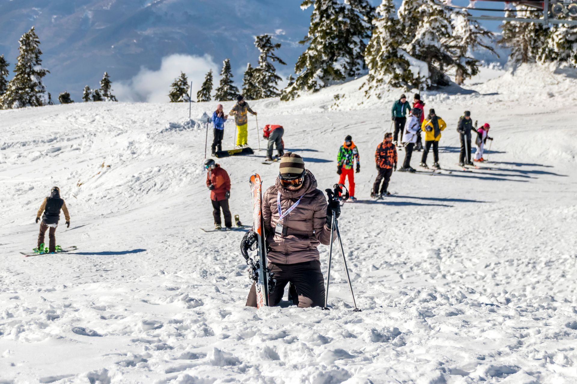 Skiers standing and climbing a snowy hill on a bright winter day