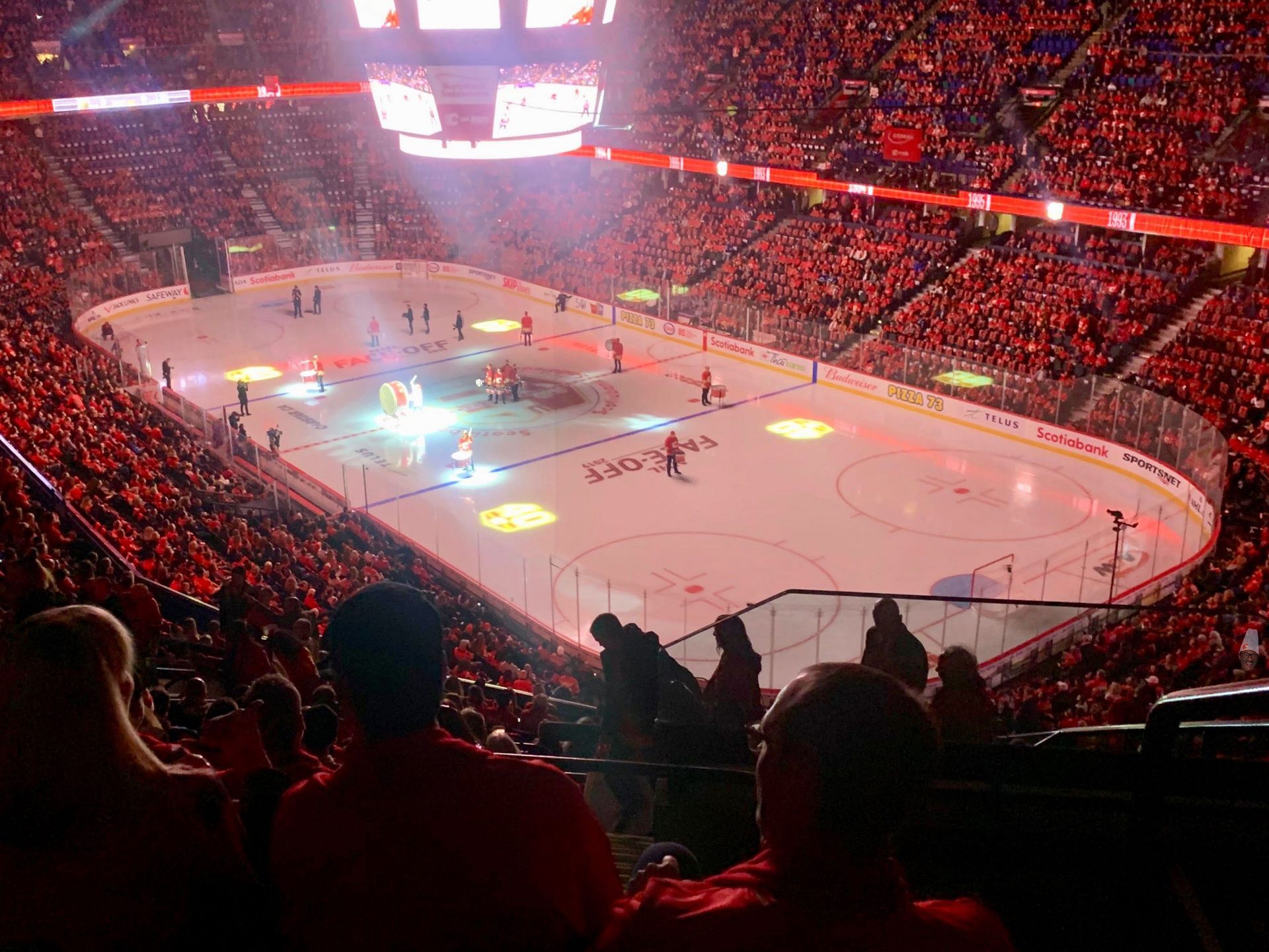 Packed hockey arena with red-lit crowd and players on the ice during a game