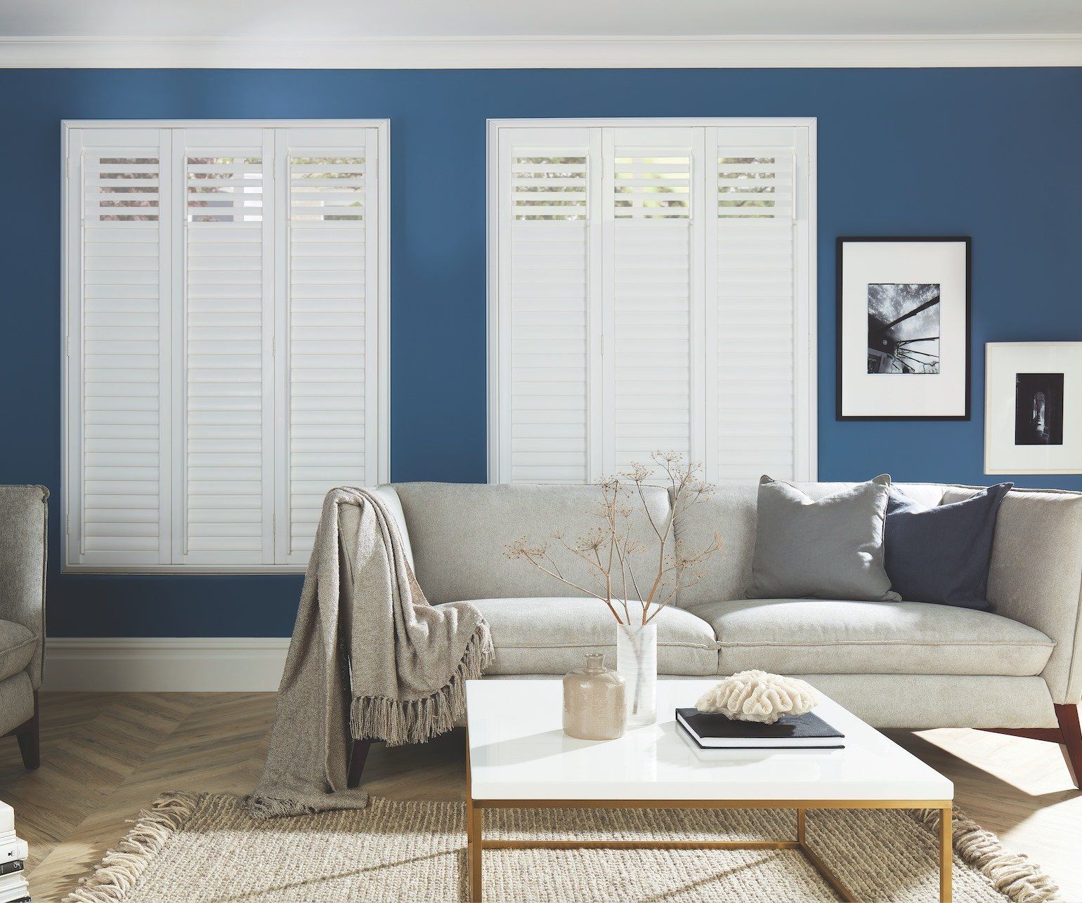 Living room with white shutters, blue wall, beige sofa, and a coffee table.