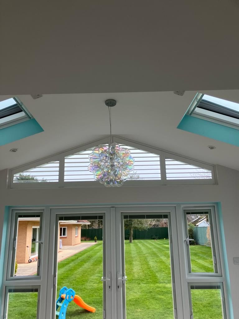 Bright, airy sunroom with French doors and clerestory windows, looking out onto a green lawn.