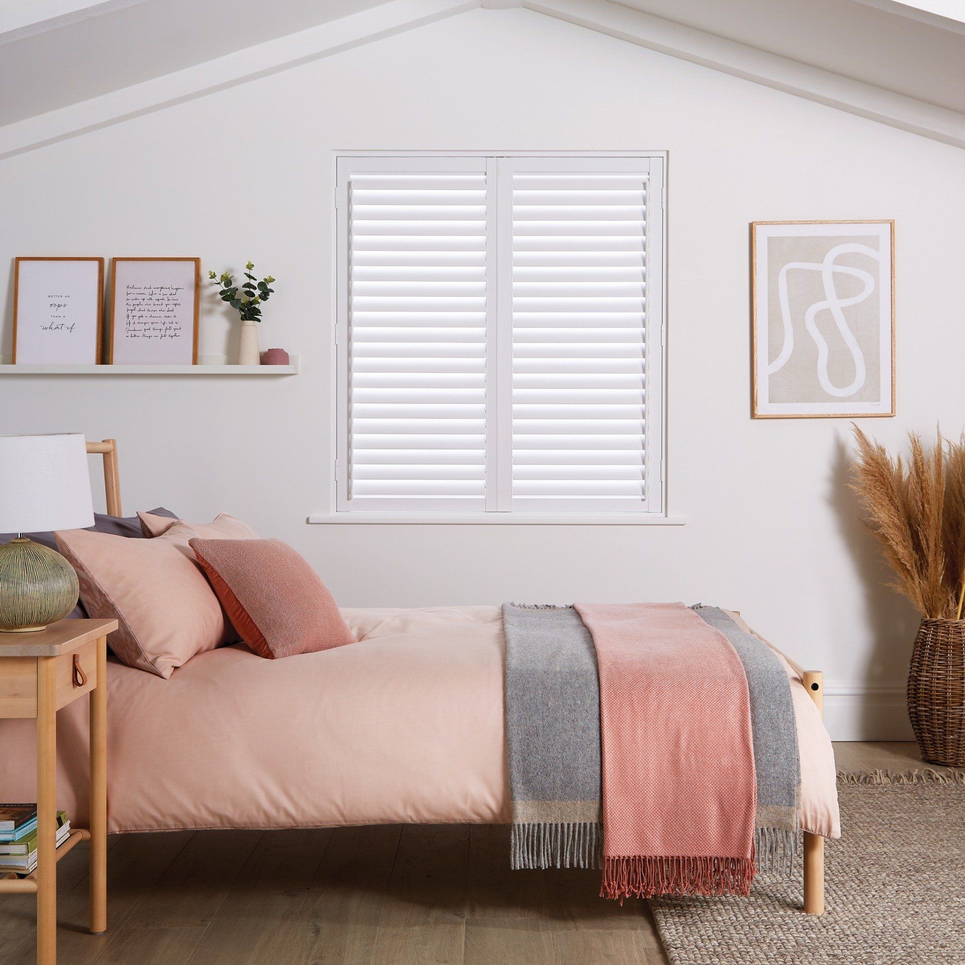 Bedroom with bed, pink bedding, white shutters, and artwork.