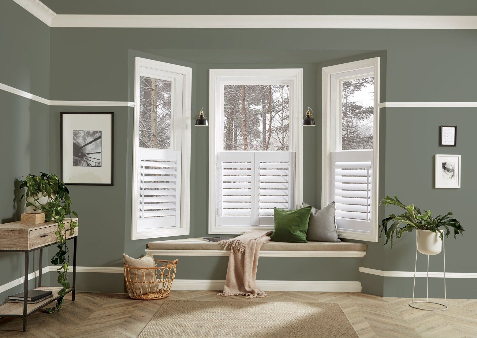 Room with bay windows, white shutters, olive walls, and a window seat with pillows.