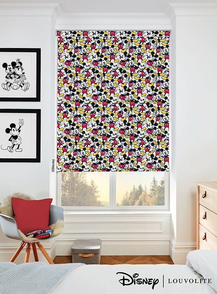 Mickey Mouse pattern roller blind, two framed Mickey prints, a chair, and a dresser in a room with a window.
