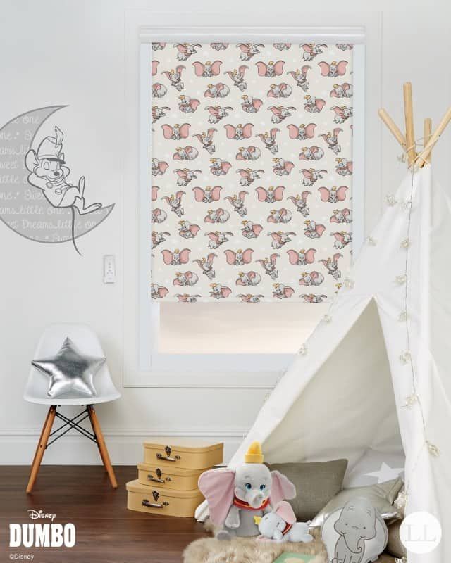 Window blind with Dumbo pattern in a child's room. Dumbo plush, teepee, star chair, and moon art.