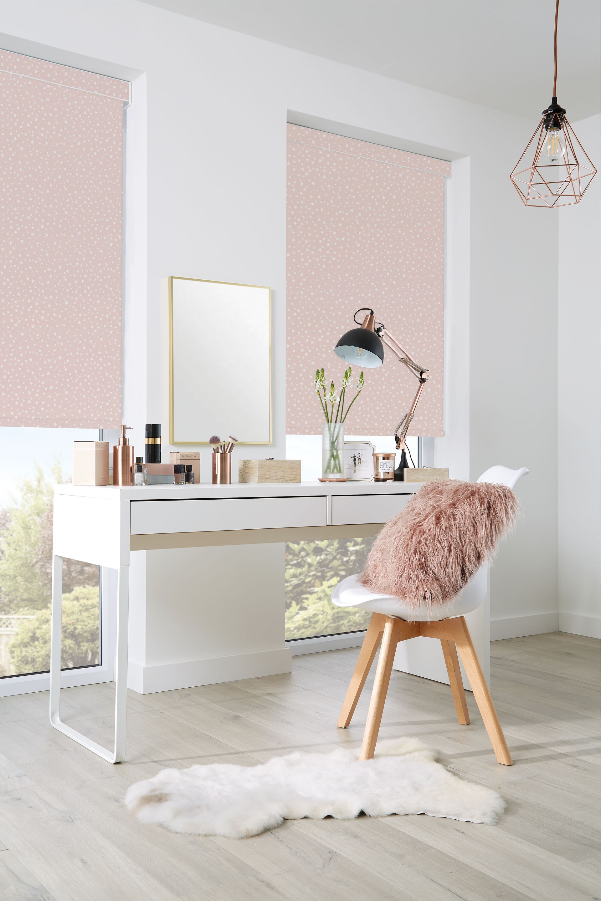 A bright room with a white desk, chair, and pink patterned window shades.