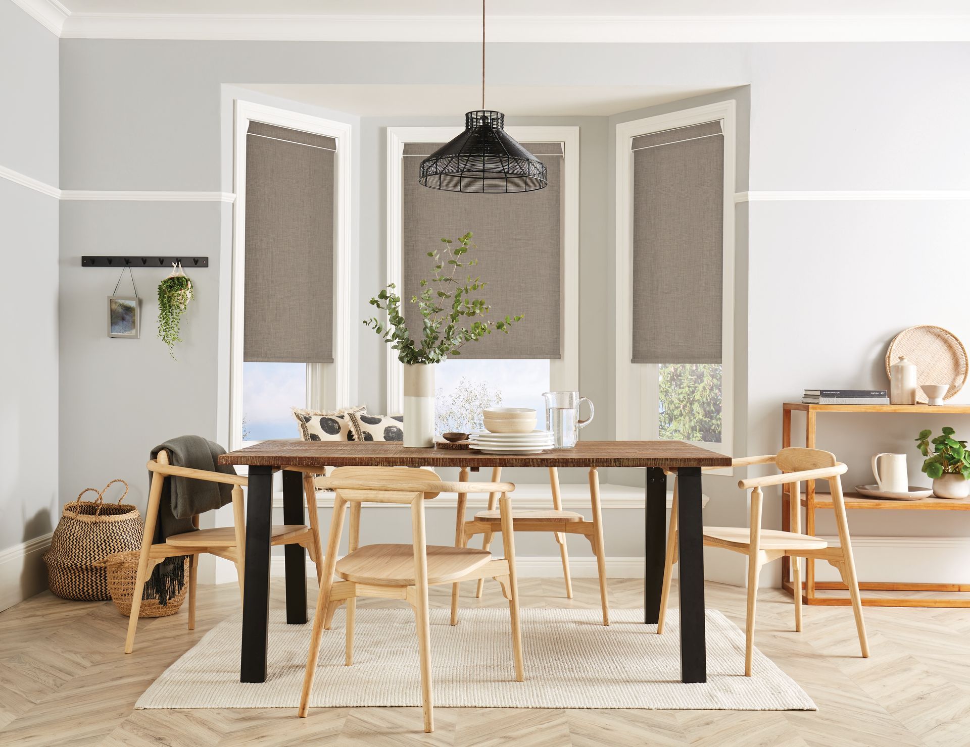 Dining room with wooden table and chairs, bay window with blinds, decorative light fixture.