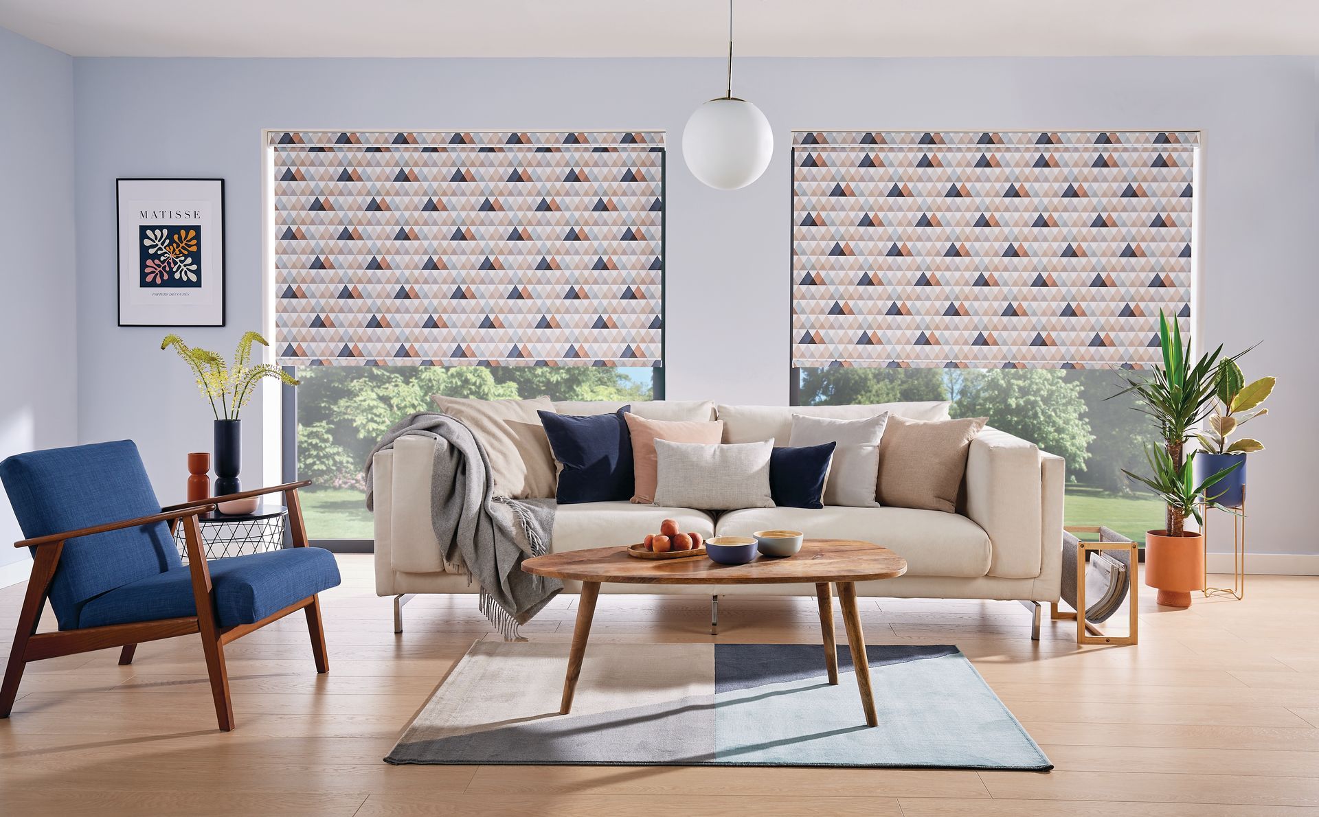 Living room with patterned window blinds, sofa, blue chair, and coffee table.