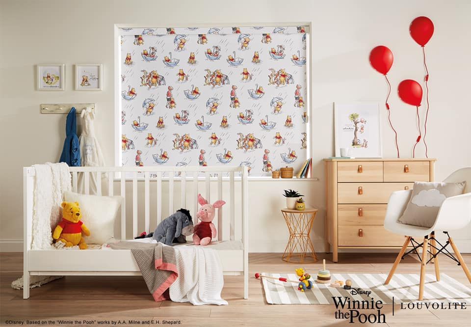 A Winnie the Pooh-themed nursery with crib, blinds, artwork, and red balloons.
