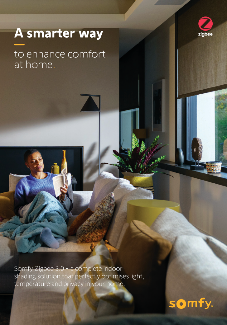 Woman relaxing on a couch, reading under the sunlight coming from the window. Product is Somfy Smart Shades.