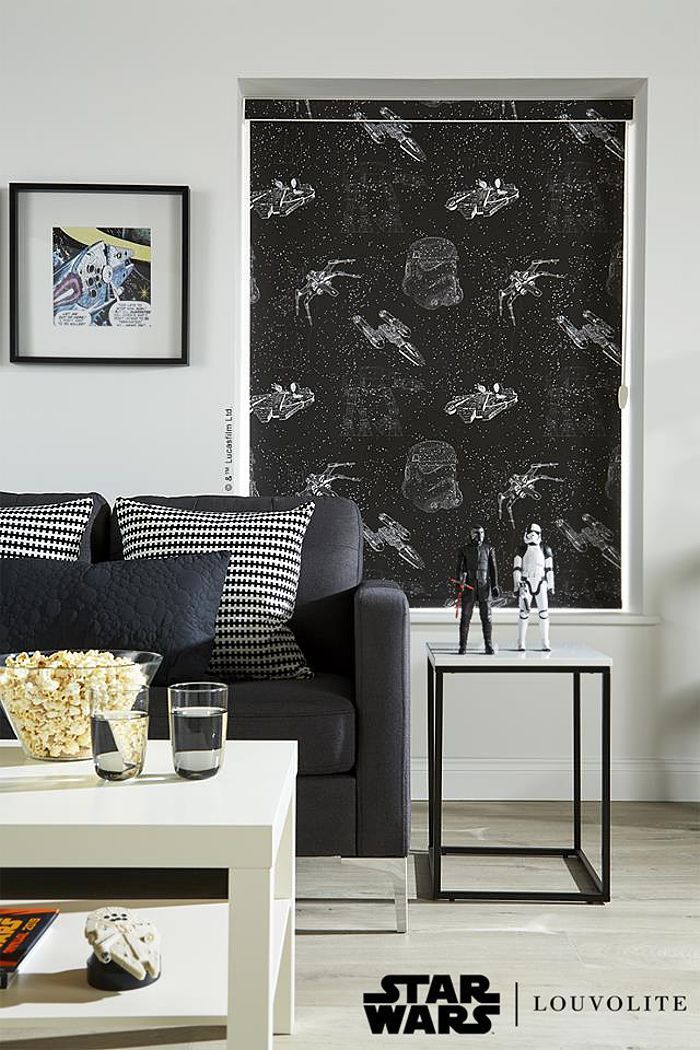 Living room with Star Wars-themed window blinds. Black sofa, white table, and framed art.