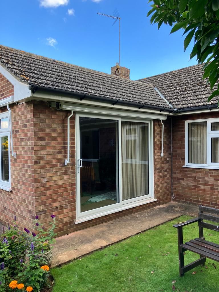 Brick house with sliding glass door, antenna, and small lawn.