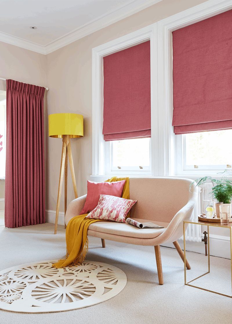 Living room with pink curtains, shades, and sofa; yellow accents; rug.