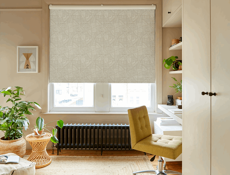 Room with a beige window shade, desk, chair, plants, and radiator.