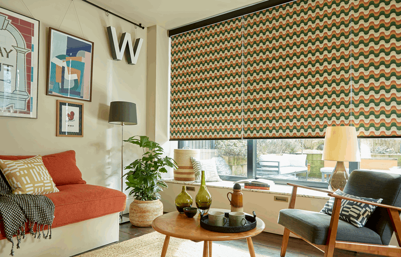 Living room with patterned window blinds, sofa, artwork, and various decor items.
