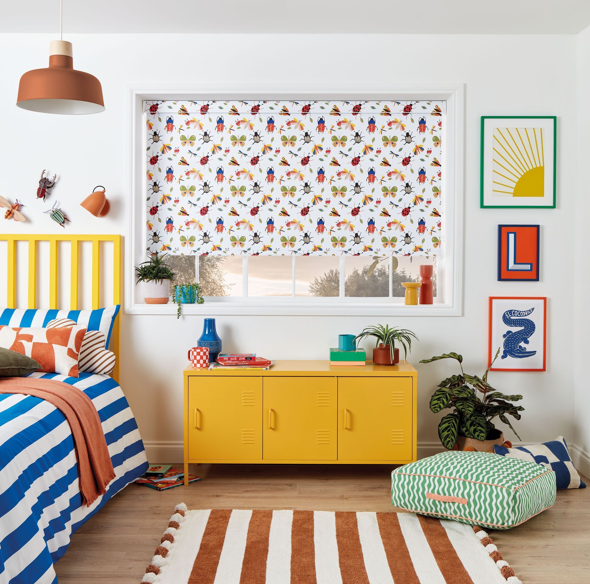 Playful bedroom with yellow furniture, striped rug and bedding, and colorful insect-patterned window blind.