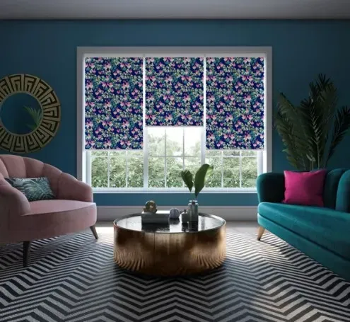 Living room with floral patterned shades, velvet furniture, and a zig-zag rug.