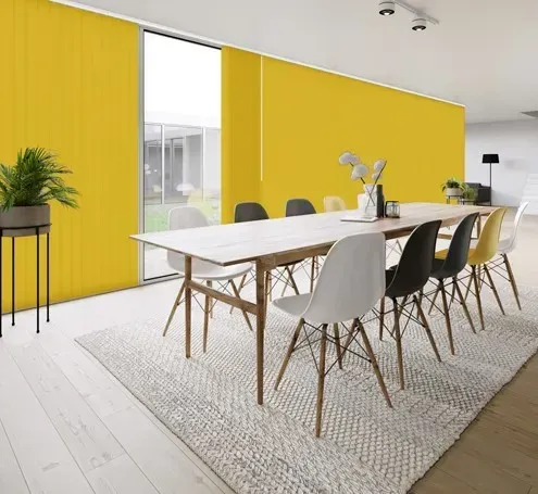 Yellow vertical blinds and wall in a modern dining room with a long table and chairs.