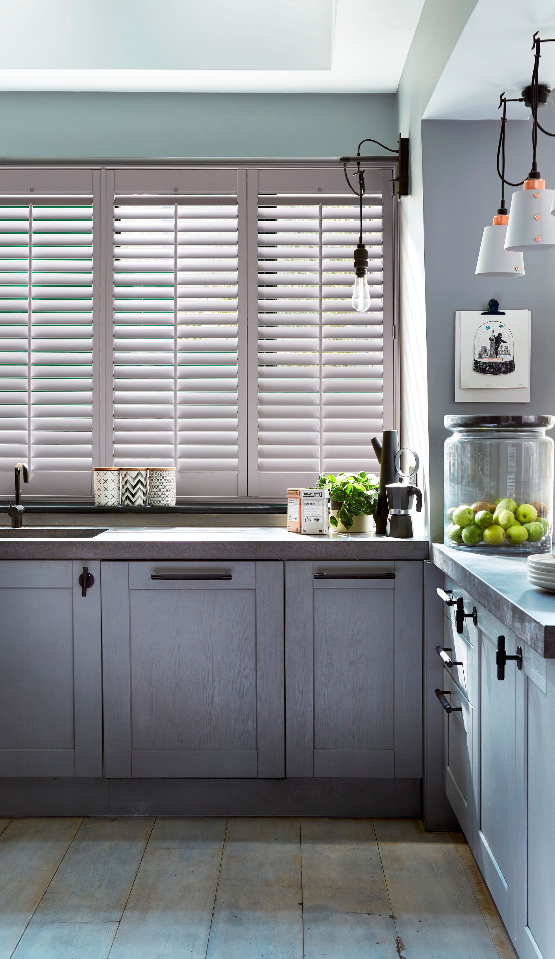 Grey kitchen with shutters and overhead lights.