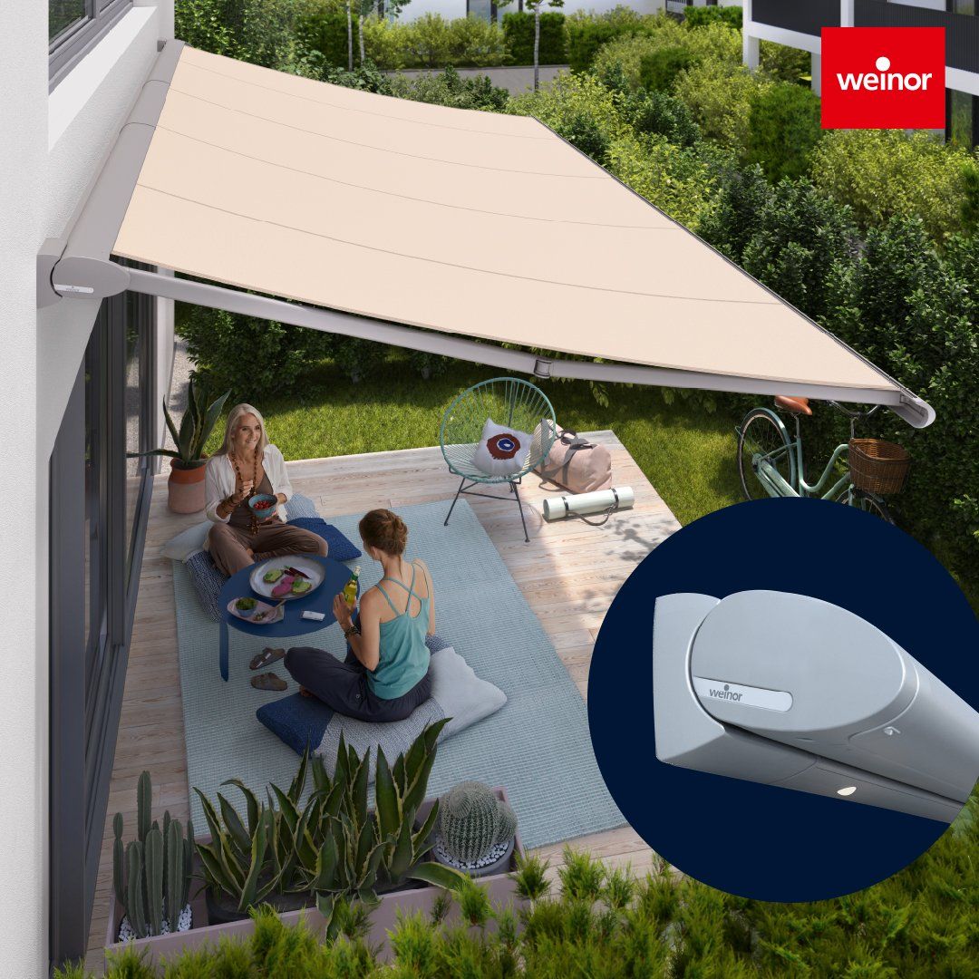 Beige awning over a patio. Two people sit at a table, enjoying the shade.