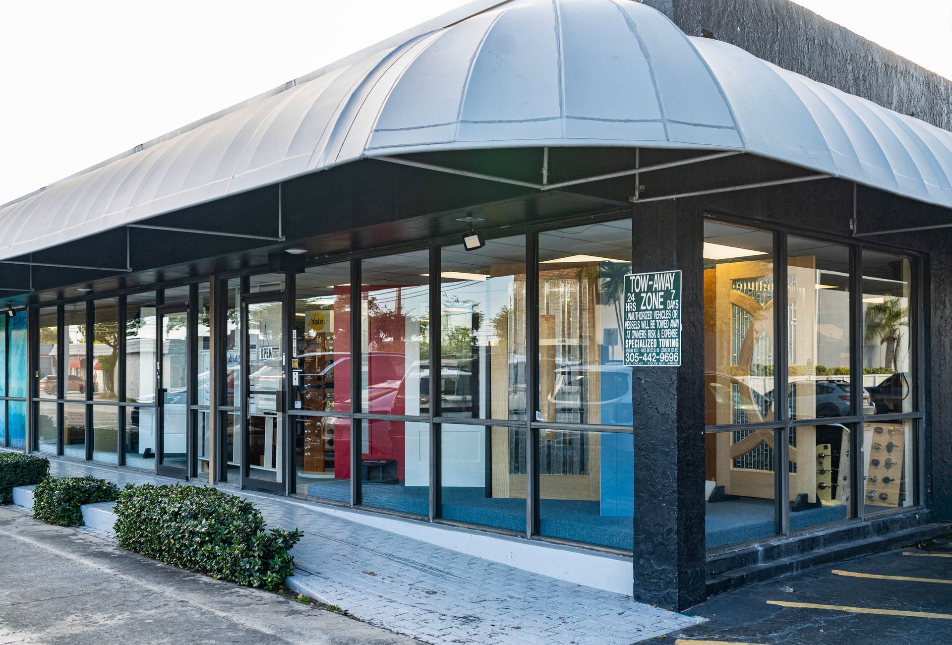 Modern storefront with large glass windows and a curved metal awning at the corner of a building