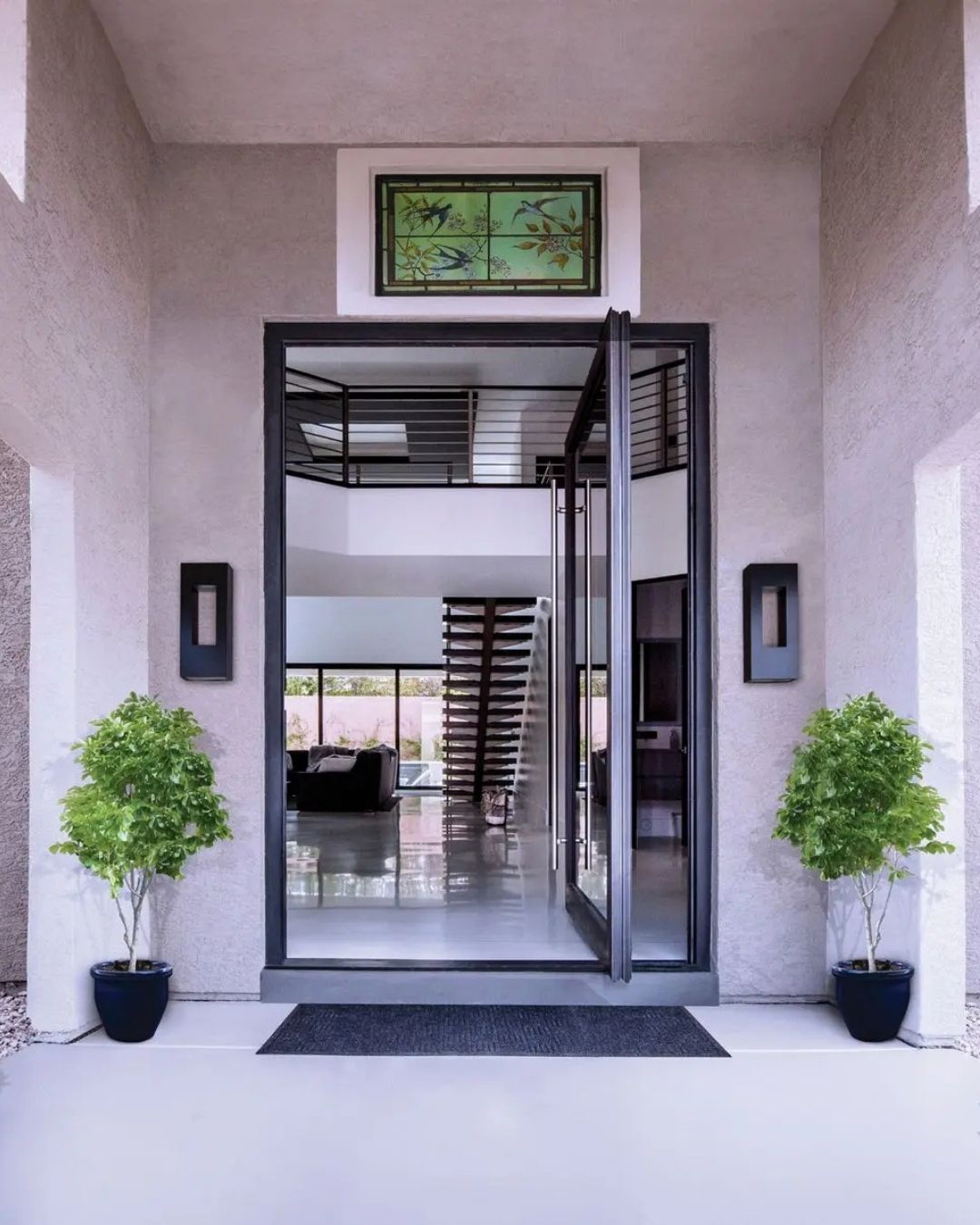Front entrance with glass double doors, potted plants, and a wall-mounted sign above the doorway.
